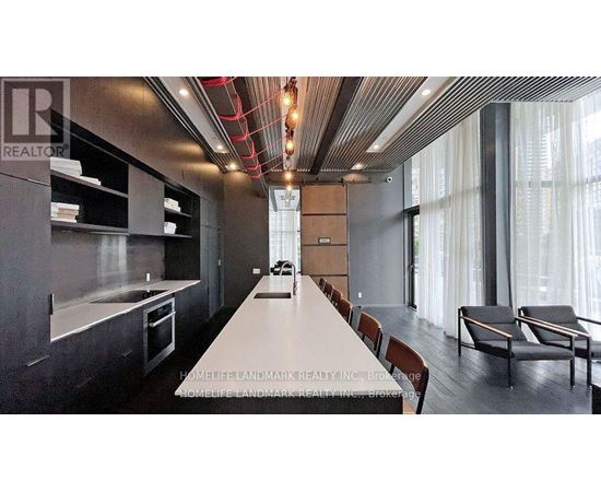 A modern kitchen with a long white table and chairs.