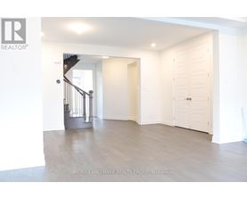 A spacious room with a staircase and a door leading to another room.