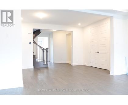 A spacious room with a staircase and a door leading to another room.