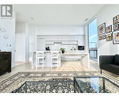 A modern kitchen with white cabinets and a black couch.