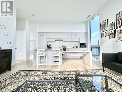 A modern kitchen with white cabinets and a black couch.