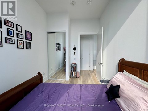 A bedroom with a purple bedspread and a bed on the left side.