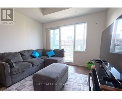 A living room with a grey couch and a small ottoman.