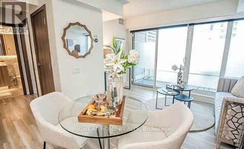 A modern living room with a glass table and a mirror on the wall.