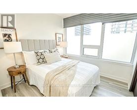 A bedroom with a bed, pillows, and a lamp.