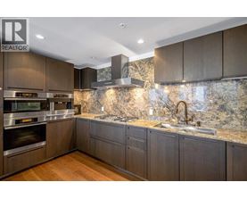 A modern kitchen with dark wood cabinets and a marble backsplash.