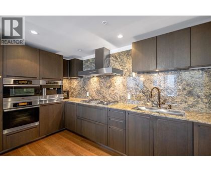 A modern kitchen with dark wood cabinets and a marble backsplash.