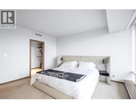 A bedroom with a large bed and a nightstand with a lamp.