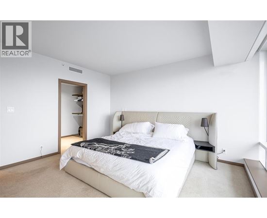 A bedroom with a large bed and a nightstand with a lamp.