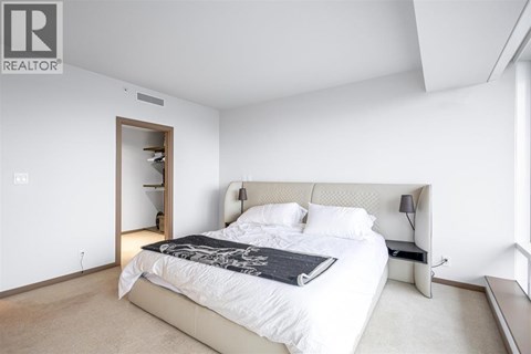 A bedroom with a large bed and a nightstand with a lamp.