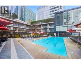 A large swimming pool in a city setting with a red umbrella.