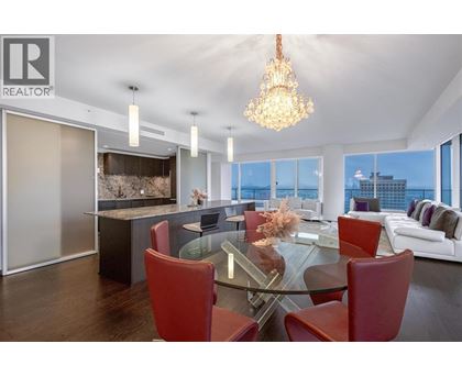 A modern dining room with a glass table and red chairs.
