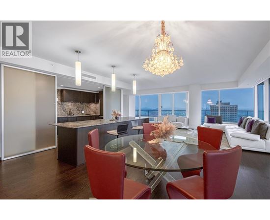 A modern dining room with a glass table and red chairs.