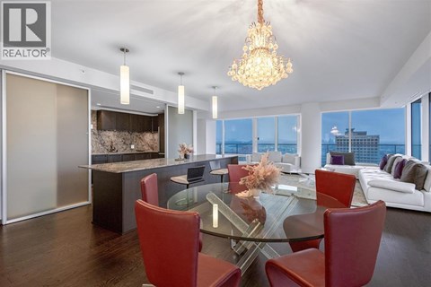 A modern dining room with a glass table and red chairs.