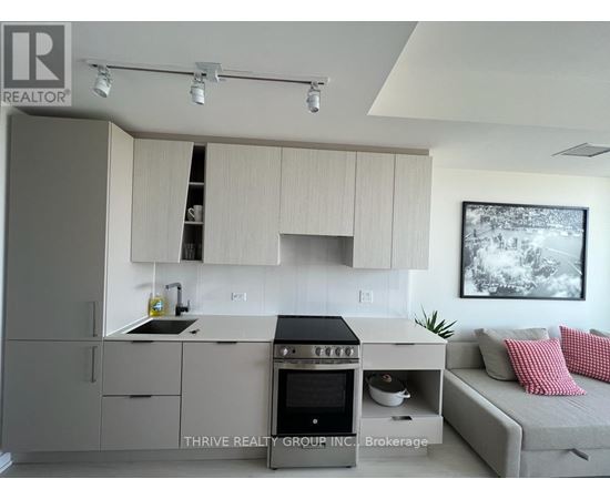 A modern kitchen with a stove top oven and a couch.