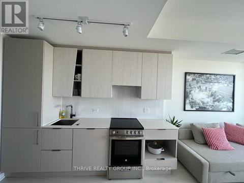 A modern kitchen with a stove top oven and a couch.