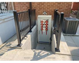 A white box with red pipes on a concrete ledge outside a brick building.