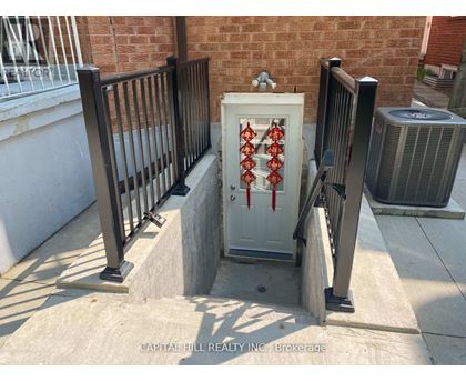 A white box with red pipes on a concrete ledge outside a brick building.