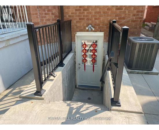 A white box with red pipes on a concrete ledge outside a brick building.
