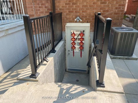 A white box with red pipes on a concrete ledge outside a brick building.