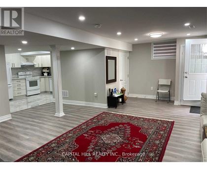 A living room with a rug in the middle and a kitchen in the background.