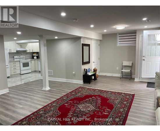 A living room with a rug in the middle and a kitchen in the background.