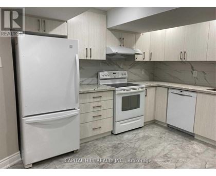 A white refrigerator stands in a kitchen with white cabinets and a marble floor.
