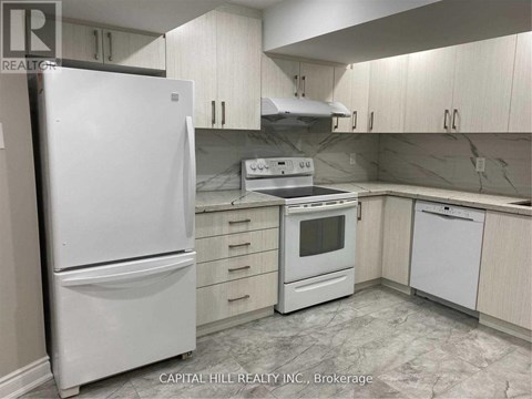 A white refrigerator stands in a kitchen with white cabinets and a marble floor.