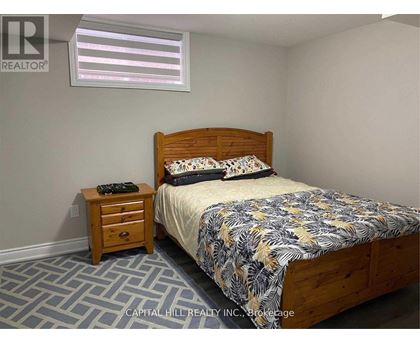 A bedroom with a bed, nightstand, and window.