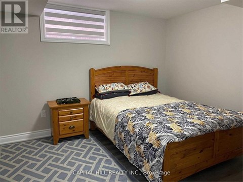 A bedroom with a bed, nightstand, and window.