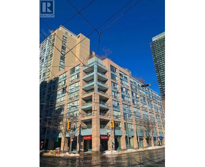A tall building with many windows and balconies is in the foreground with a blue sky in the background.