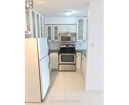 A white kitchen with a refrigerator on the left and a stove top oven in the middle.