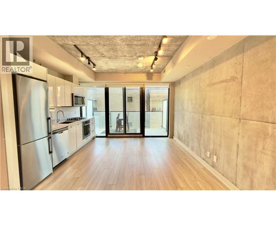 A kitchen with a refrigerator and wooden floors.