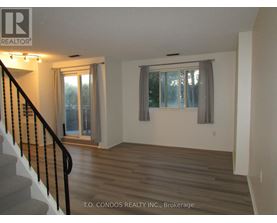 A room with a staircase and a window with a grey curtain.