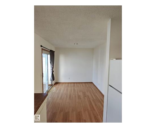 A room with wooden flooring and white walls.
