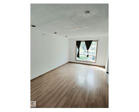 A room with wooden flooring and a window with a view of a street.