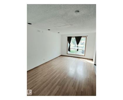 A room with wooden flooring and a window with a view of a street.