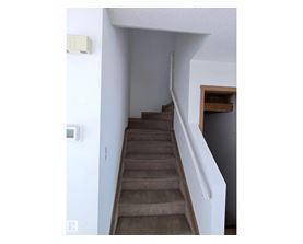 A staircase with a white railing and a brown carpet.