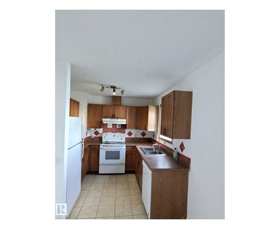 A kitchen with white appliances and wooden cabinets.