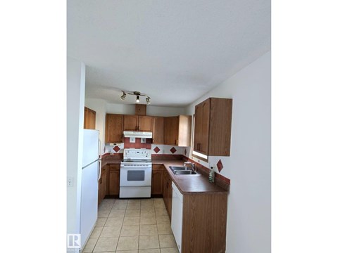 A kitchen with white appliances and wooden cabinets.