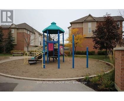 A playground with a blue and green structure in the middle of a sandy area.