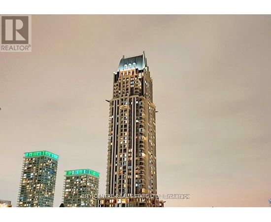 A tall building with a glass facade stands in front of two shorter buildings.