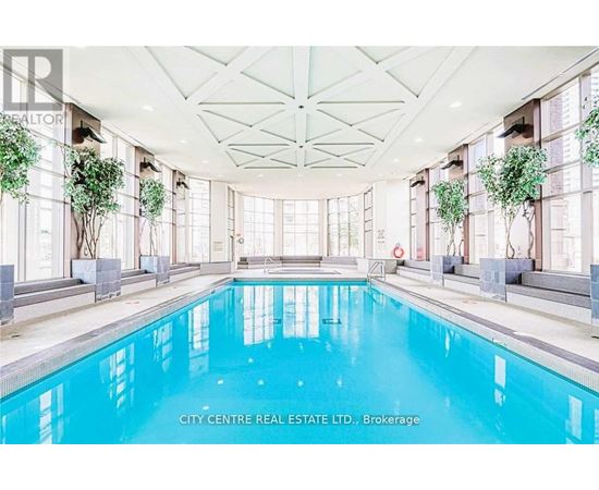 A large indoor swimming pool with a glass ceiling and a white floor.