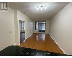 A spacious room with wooden floors and a large window.