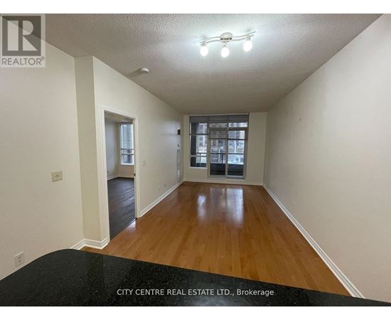 A spacious room with wooden floors and a large window.