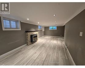 A spacious room with a fireplace and wooden flooring.