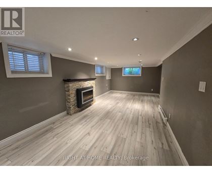 A spacious room with a fireplace and wooden flooring.
