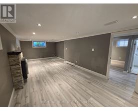 A spacious room with wooden flooring and a stone fireplace.