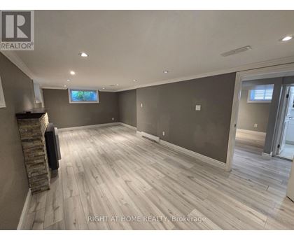 A spacious room with wooden flooring and a stone fireplace.