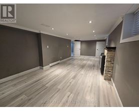 A room with wooden flooring and a stone fireplace.